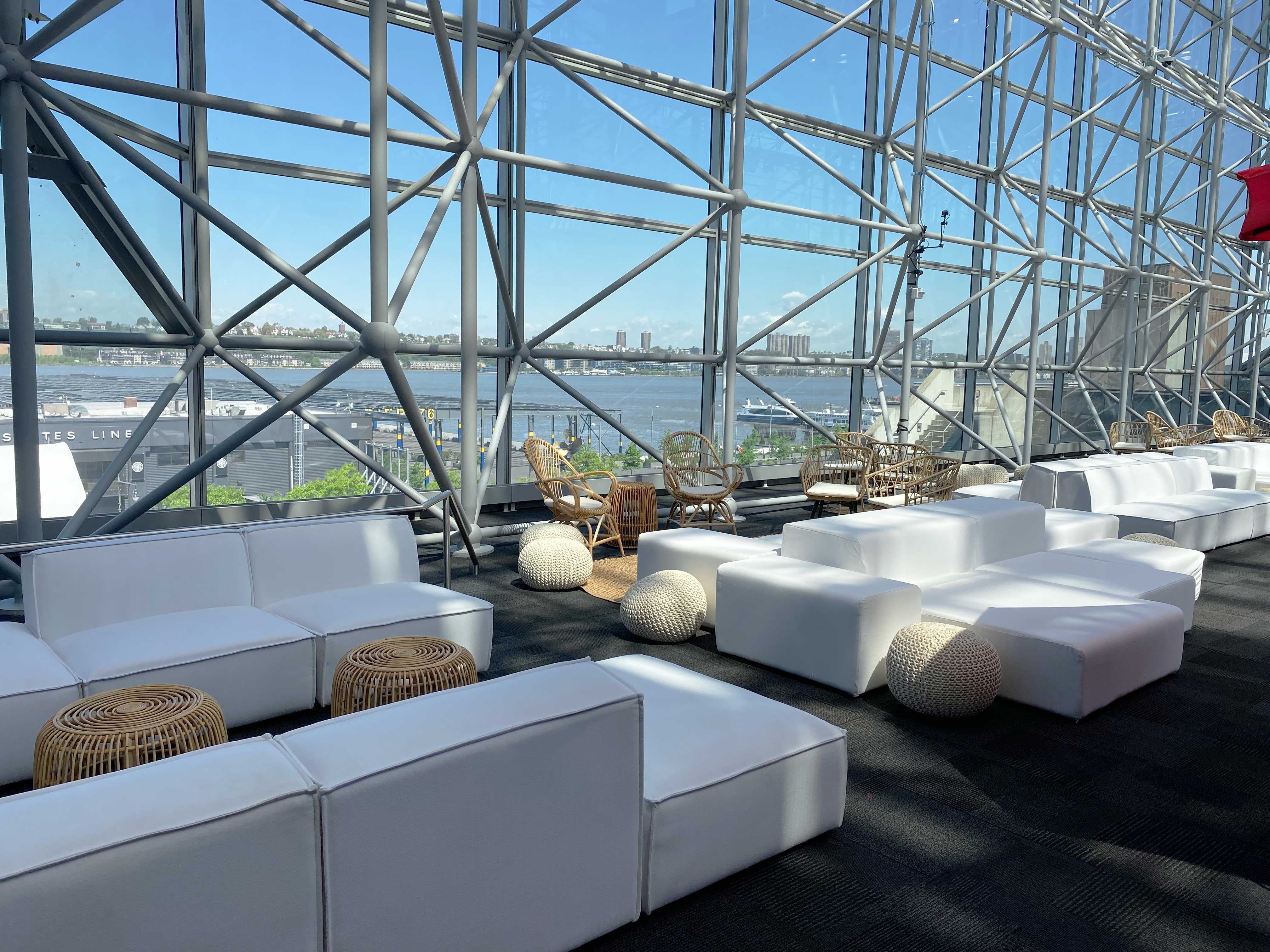 White couches in front of see through glass panels with blue sky.